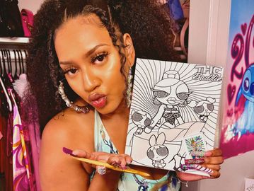 Woman holding a coloring sheet of a Powerpuff Girls design.