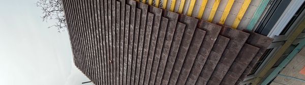 Roof with half wooden shingles installed and half exposed wooden battens.