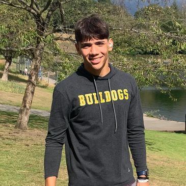 Young man smiling outdoors in a Bulldogs hoodie.