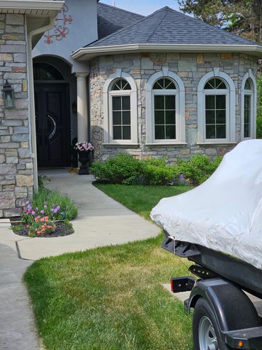 Stone house with arched windows and a covered boat trailer on the lawn.