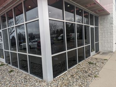 Corner entrance of a building with reflective glass windows and gravel landscaping.