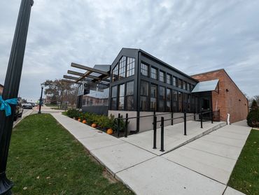 Modern pizzeria with large windows and pumpkins along the sidewalk.