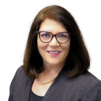 Professional woman with glasses and dark hair smiling in business attire.