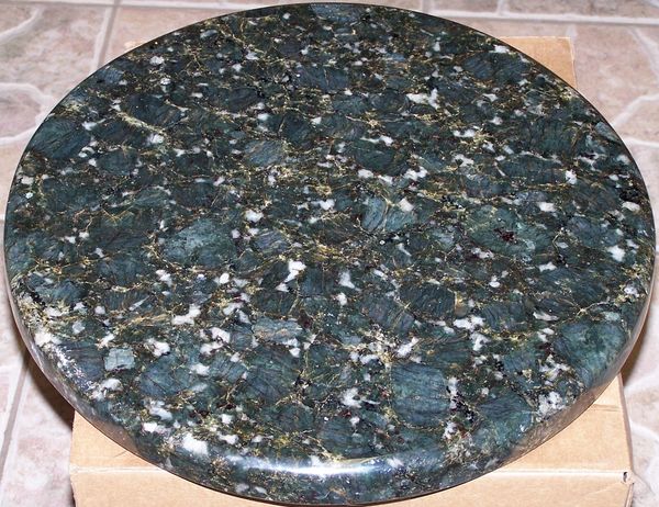 Round polished granite slab with dark green and white speckles.