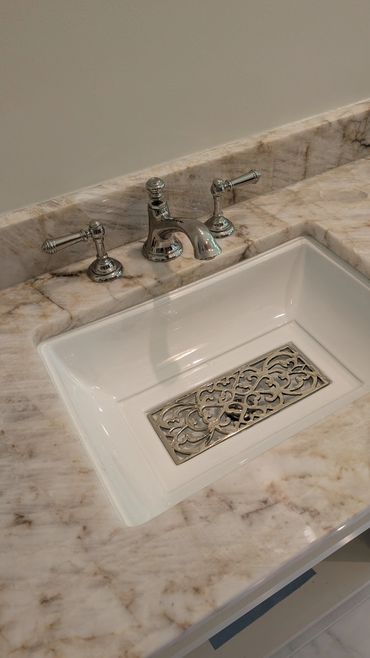Elegant bathroom sink with ornate metal drain and marble countertop.