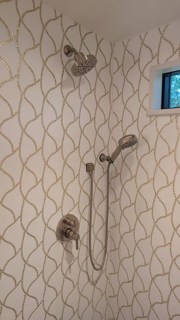 Modern shower with a unique gold-patterned tile design and dual shower heads.