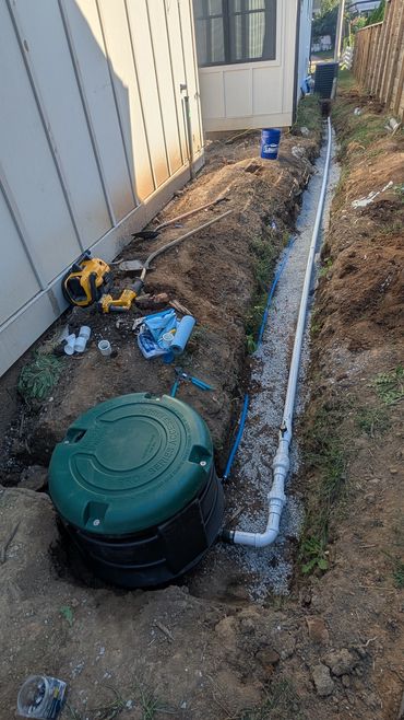 Outdoor plumbing installation with pipes and tools along a house side.