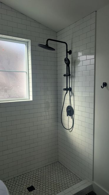 Modern shower with white subway tiles and black fixtures.