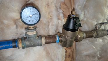Pressure gauge and valve connected to copper piping against insulation.