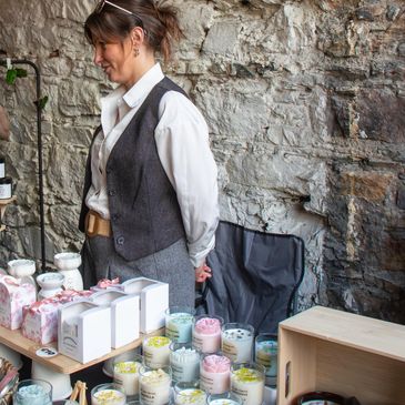 Woman selling various scented candles at a market stall.