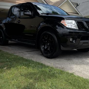 Black pickup truck parked in a residential driveway with houses in the background.