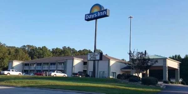 Exterior view of a Days Inn motel with cars parked outside under a clear sky.
