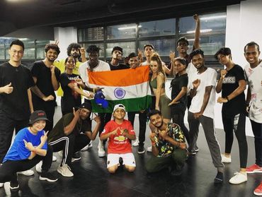 Group of diverse young people posing with the Indian flag indoors.