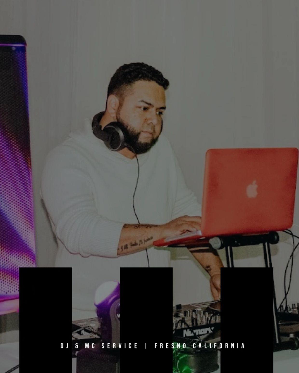 DJ focused on mixing music with headphones and a laptop in a studio setup.
