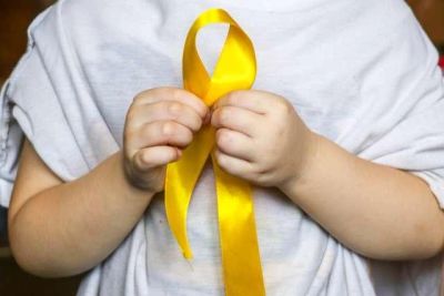 Child holding a yellow ribbon in hands.