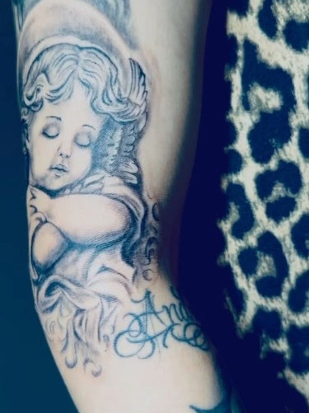Tattoo of a serene angel with closed eyes on an arm.