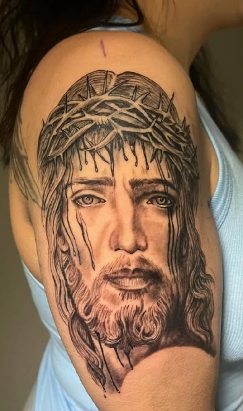 Tattoo of Jesus wearing a crown of thorns on the upper arm.
