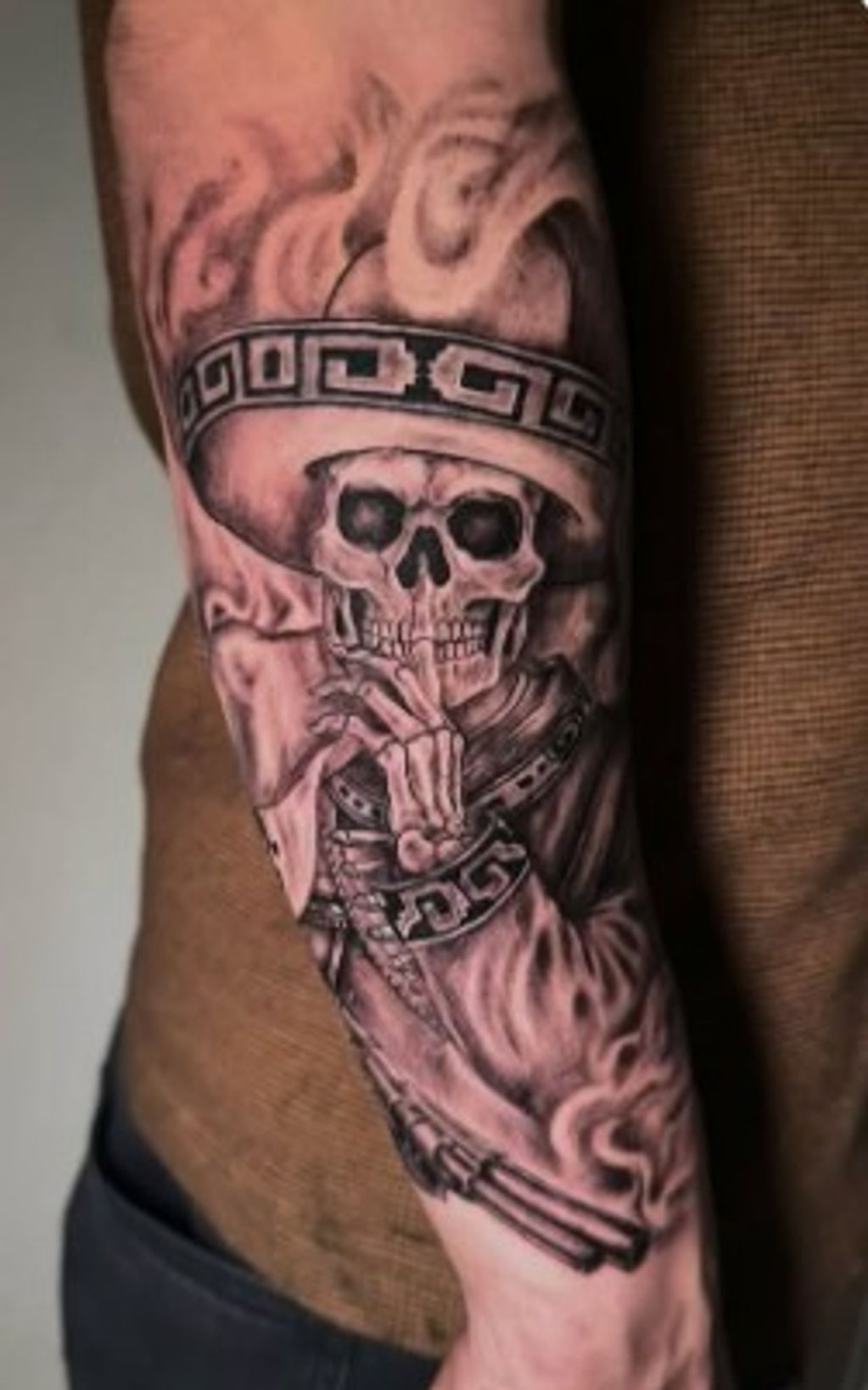 Tattoo of a skeleton wearing a hat and smoking a cigarette.