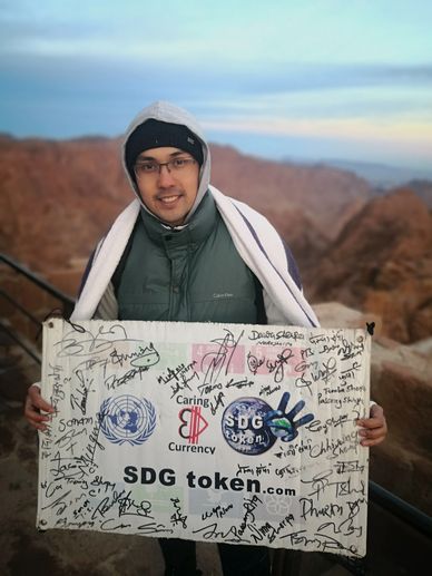 Doctor holds SDGtoken.com Everest  Summit Banner, signed by Sherpa who touched it on the way to top