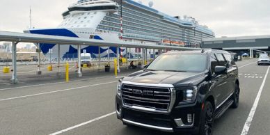 Black SUV parked near a large cruise ship at the port.