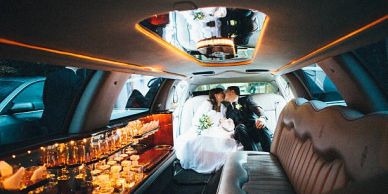 Newlyweds kissing inside a luxury limousine.