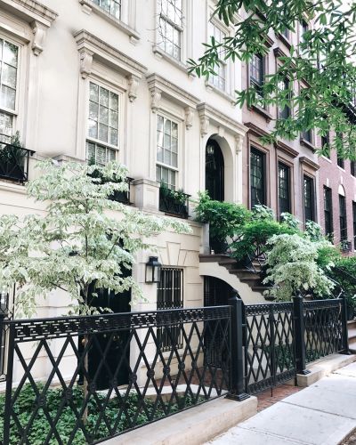 Elegant townhouse with greenery and black iron fence.