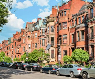 Row of historic brick townhouses with parked cars.