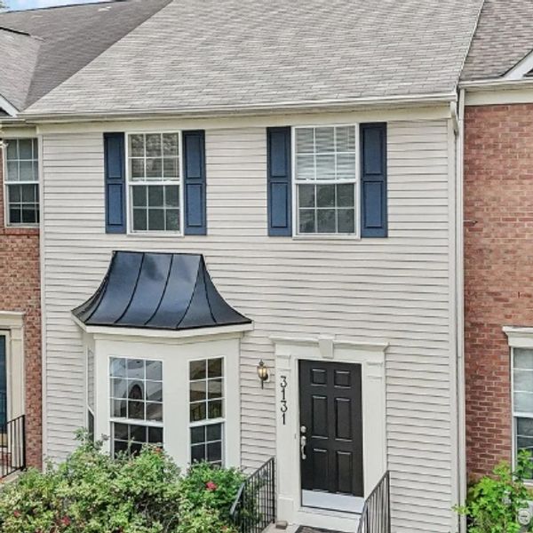 Two-story townhouse with beige siding and black door.