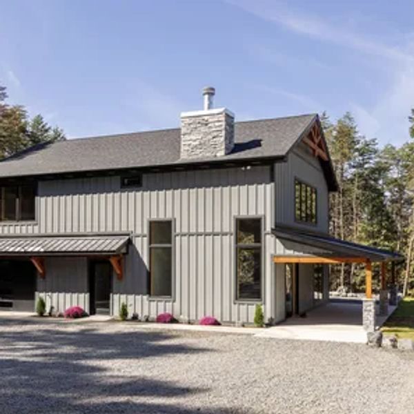 Modern gray house with vertical siding and stone chimney.