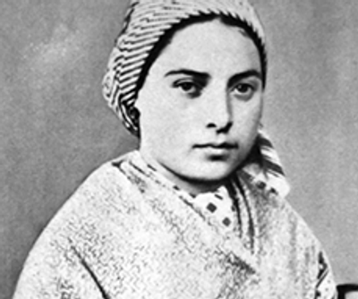 Black and white portrait of a young girl wearing a headscarf and shawl.