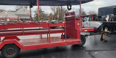Red horse-drawn carriage with festive decorations on a paved road.