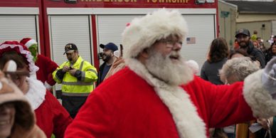 Santa Claus in festive parade with Anderson Township fire truck in background.