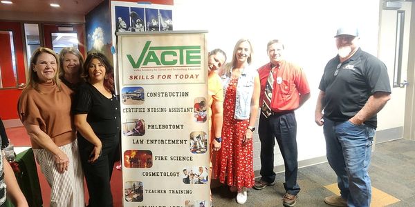 Group of six people standing next to a VACTE skills banner.