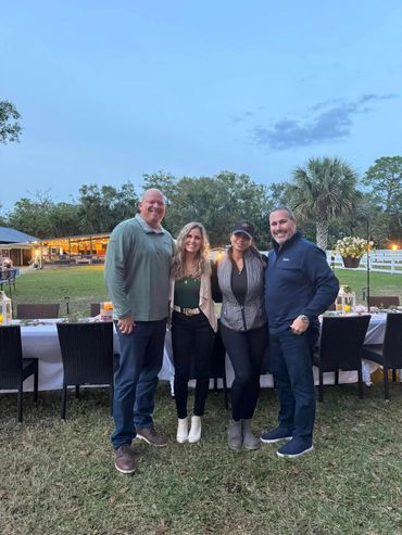 Jeannette and Larry Jarnes standing with two guests in front of the Farm to Table dinner table.