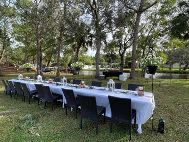 The dinner table in front of a beautiful pond and trees.