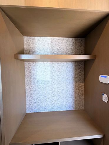 Grey scallop pattern wallpaper lining a wood built-in cabinet niche