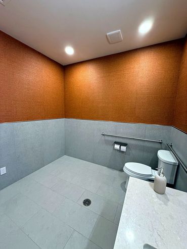 Orange vinyl wallcovering over tile wainscot in an accessible commercial restroom