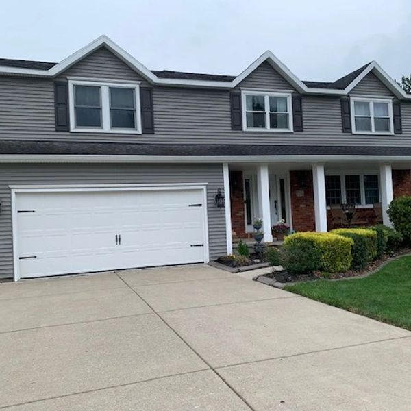 Two-story suburban house with gray siding and a white garage door.