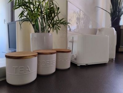 Three labeled ceramic jars and a white toaster on a kitchen counter.