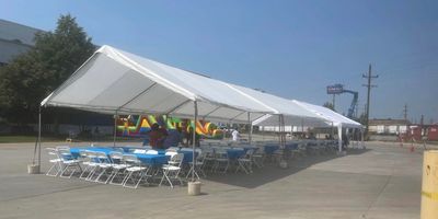 Long white tent with chairs and tables set up outside.