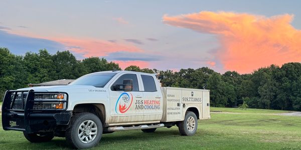 J&S Heating and Cooling service truck parked on grass.
