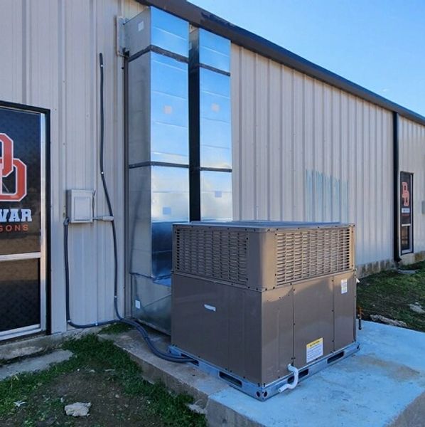 Outdoor HVAC unit beside metal building.