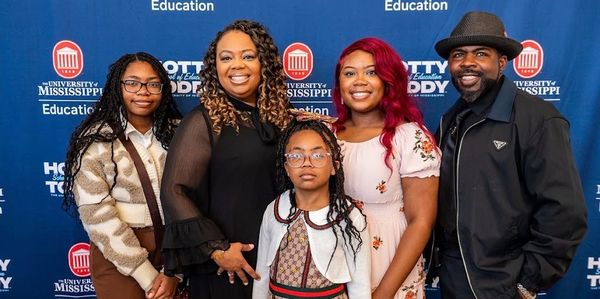 Group of five people posing at an education event.