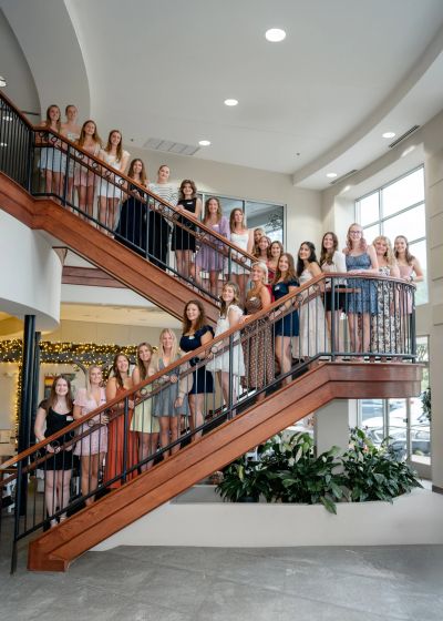 Group photo of young women on a staircase indoors.