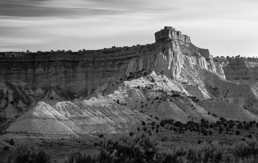 Black and white landscape photograph of layered rock formations and mesas under a dramatic sky.