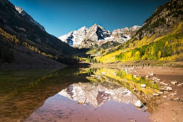 Color landscape photograph of a mountain reflected in a calm alpine lake.