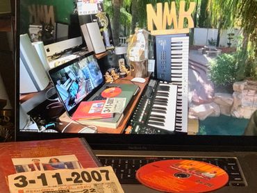 A laptop displays a music studio setup with keyboards and a book, alongside a CD and booklet dated 3-11-2007.