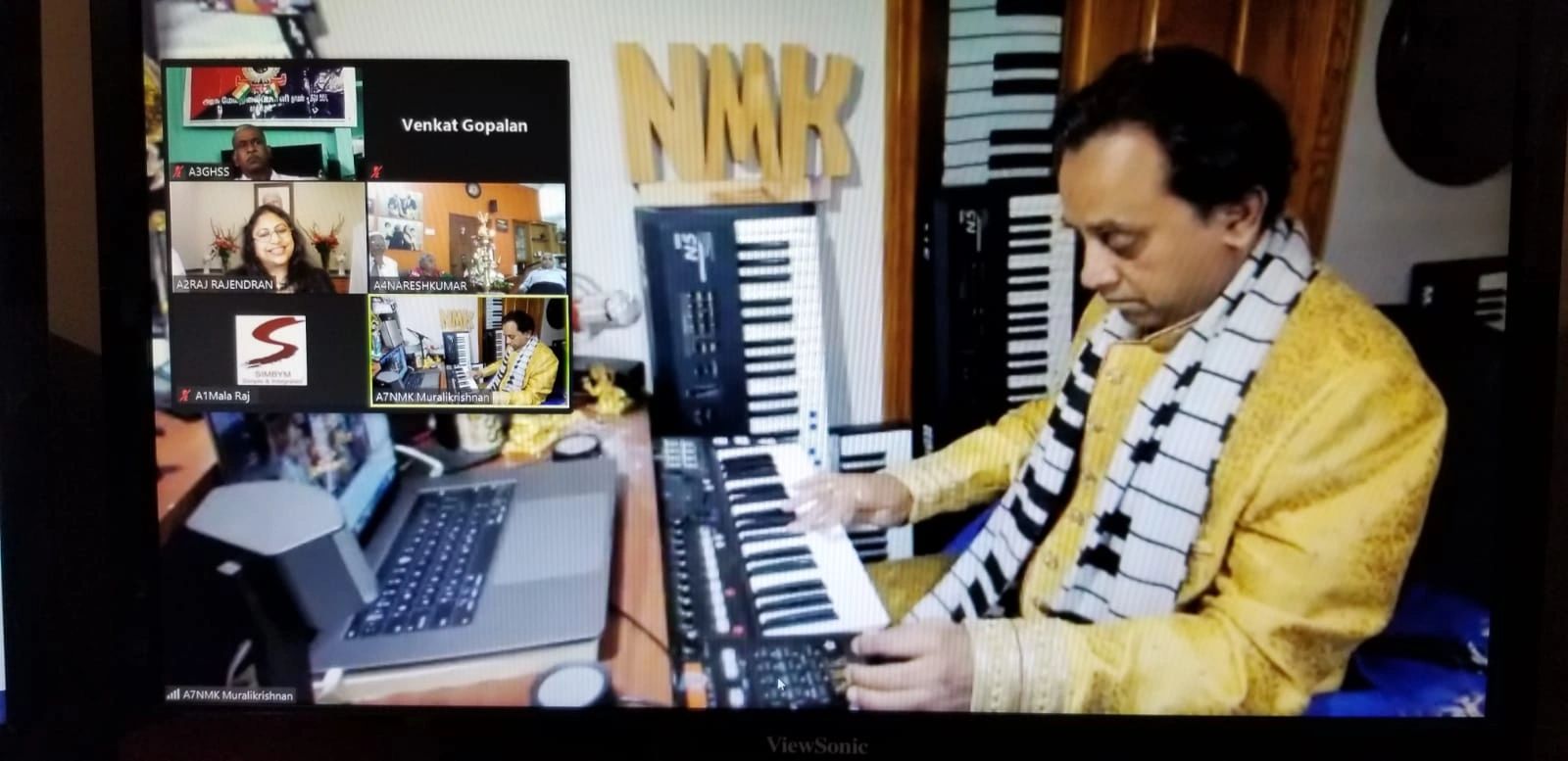 Man in yellow kurta playing keyboard during a virtual meeting.