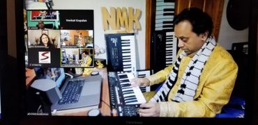 Man in yellow kurta playing keyboard during a virtual meeting.