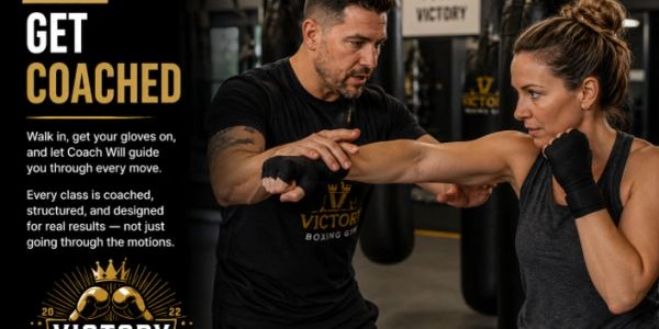Coach guiding a woman through boxing training at Victory Boxing gym.